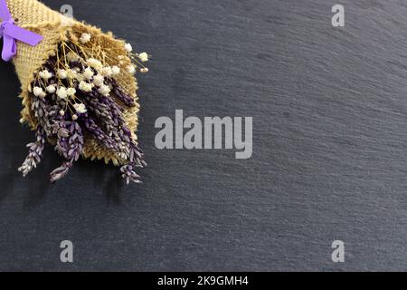 Blumenstrauß mit getrocknetem Lavendel und weißen Blumen auf schwarzem Hintergrund Stockfoto