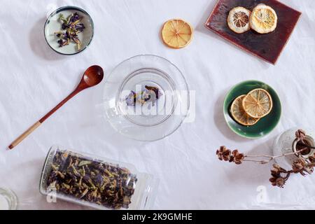 Blick von oben auf getrocknete Schmetterlingserbsen oder Clitoria ternatea und getrocknete Zitronenscheiben für die Zubereitung eines gesunden und heilenden Kräutertees Stockfoto