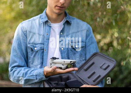 Nahaufnahme einer Quadrikopter-Drohne in selektiver Fokusansicht neben der Reisetasche in den Händen eines kleinen Jungen Stockfoto