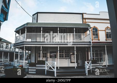 Alte hölzerne Backwarenfassade in einer kleinen Stadt mit Tischen und Stühlen draußen in einer ruhigen, entspannten Umgebung abseits der Zivilisation, der westlichen Nachbarschaft, neuseelands Stockfoto