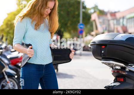 Eine rothaarige Frau legt einen Gürtel an, um ein Motorrad zu fahren Stockfoto