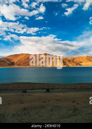 Ladakh, Indien - 19. Juni 2022 : Biker genießen einen schönen Panoramablick auf den Pangong Lake. Das höchste Salzwasser der Welt, umgeben von Bergen.Vertikal oder p Stockfoto