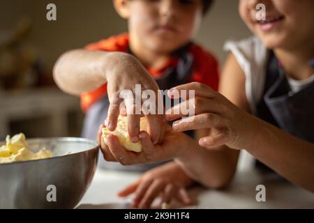 Nahansicht der Hände von Kindern, die Butter einlegen Stockfoto
