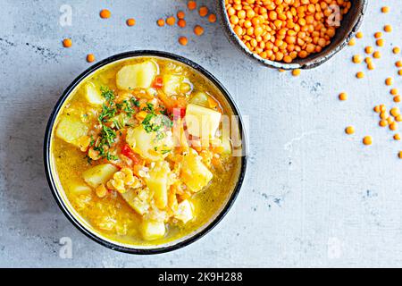 Suppe mit roten Linsen und Gemüse in einer Schüssel auf blauem Hintergrund.Traditionelles Gericht der türkischen oder arabischen Küche, vegane gesunde Lebensmittel. Stockfoto