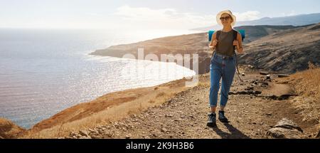 Pilger auf der Pilgerfahrt. Junge lächelnde Frau auf dem Weg zur Küste des Ozeans. Banner mit Kopierraum Stockfoto