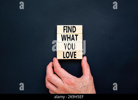 Finden Sie, was Sie lieben Symbol. Concept Words Finden Sie auf Holzblöcken, was Sie lieben. Schöne schwarze Tabelle schwarzen Hintergrund. Geschäftsmann Hand. Business, Psyc Stockfoto