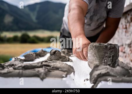 Installation der weißen Polystyrol-Wärmedämmung, Detail auf Arbeiter Hand legen grauen Kleber Zement auf weißen Brettern Stockfoto