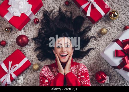 Oben sehen Foto von staunenden fröhlichen Person Hände berühren Wangen legen Teppich Boden drinnen Stockfoto