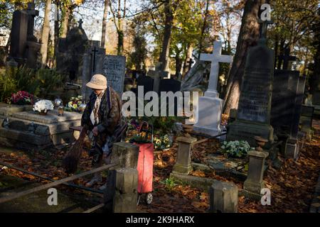 Eine ältere Frau sah, wie sie auf dem historischen Powazki Friedhof ein Grab reinigte. Der Allerheiligste Tag, der am 1.. November stattfindet, ist ein Feiertag in Polen und einer der wichtigsten katholischen Feiertage im Laufe des Jahres. Diejenigen, die ihre Angehörigen verloren haben, gehen auf die Friedhofs, um den Toten ihre Achtung zu erweisen. Sie brennen Kerzen auf den Gräbern und bringen Blumen. Es wird manchmal auch als der Tag der Erinnerung an die, die gegangen sind, bezeichnet. Stockfoto