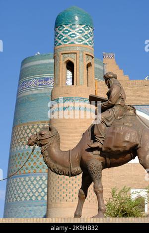 Khiva Usbekistan - Denkmal der Kamelfiguren der alten Seidenstraßen auf der UNESCO-Stätte IInchon Qala mit dem Minarett von Kalta im Hintergrund Stockfoto