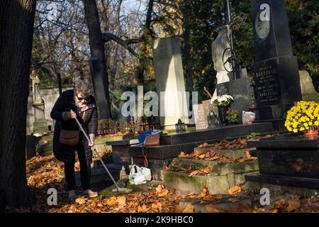 Warschau, Polen. 27. Oktober 2022. Eine ältere Frau sah auf dem historischen Powazki-Friedhof fegende Blätter. Der Allerheiligste Tag, der am 1.. November stattfindet, ist ein Feiertag in Polen und einer der wichtigsten katholischen Feiertage im Laufe des Jahres. Diejenigen, die ihre Angehörigen verloren haben, gehen auf die Friedhofs, um den Toten ihre Achtung zu erweisen. Sie brennen Kerzen auf den Gräbern und bringen Blumen. Es wird manchmal auch als der Tag der Erinnerung an die, die gegangen sind, bezeichnet. (Foto von Attila Husejnow/SOPA Images/Sipa USA) Quelle: SIPA USA/Alamy Live News Stockfoto