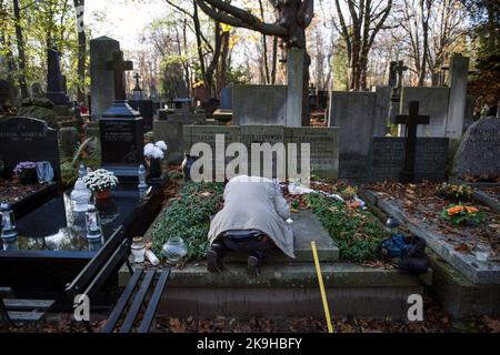 Warschau, Polen. 27. Oktober 2022. Ein Mann sah, wie er ein Grab auf dem historischen Powazki Friedhof reinigte. Der Allerheiligste Tag, der am 1.. November stattfindet, ist ein Feiertag in Polen und einer der wichtigsten katholischen Feiertage im Laufe des Jahres. Diejenigen, die ihre Angehörigen verloren haben, gehen auf die Friedhofs, um den Toten ihre Achtung zu erweisen. Sie brennen Kerzen auf den Gräbern und bringen Blumen. Es wird manchmal auch als der Tag der Erinnerung an die, die gegangen sind, bezeichnet. (Foto von Attila Husejnow/SOPA Images/Sipa USA) Quelle: SIPA USA/Alamy Live News Stockfoto