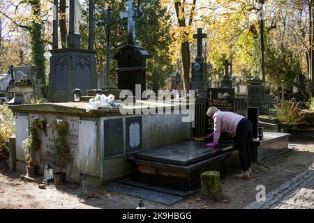 Warschau, Polen. 27. Oktober 2022. Eine Frau sah, wie sie ein Grab auf dem historischen Powazki Friedhof reinigte. Der Allerheiligste Tag, der am 1.. November stattfindet, ist ein Feiertag in Polen und einer der wichtigsten katholischen Feiertage im Laufe des Jahres. Diejenigen, die ihre Angehörigen verloren haben, gehen auf die Friedhofs, um den Toten ihre Achtung zu erweisen. Sie brennen Kerzen auf den Gräbern und bringen Blumen. Es wird manchmal auch als der Tag der Erinnerung an die, die gegangen sind, bezeichnet. (Foto von Attila Husejnow/SOPA Images/Sipa USA) Quelle: SIPA USA/Alamy Live News Stockfoto