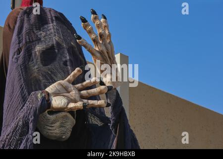 Gruseliger Totenkopf in schwarzem Schleier und gekreuzten Knochenhände begrüßt die Gäste auf der halloween Party. Halloween draußen Dekorationen. Stockfoto