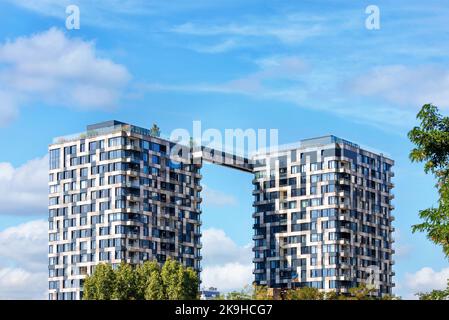 Pixel-Design der Fassade von mehrstöckigen Zwillingstürmen von Wohngebäuden gegen den blauen Sommerhimmel. Stockfoto