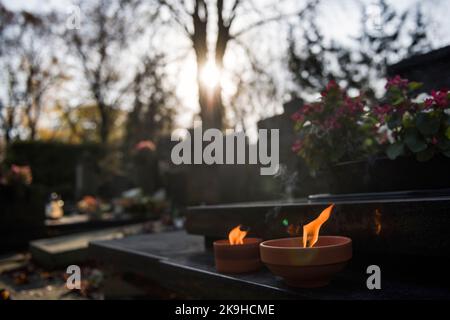 Warschau, Mazowieckie, Polen. 27. Oktober 2022. Auf einem Grab auf dem historischen Powazki-Friedhof brennen Kerzen. Der Allerheiligste Tag, der am 1.. November stattfindet, ist ein Feiertag in Polen und einer der wichtigsten katholischen Feiertage im Laufe des Jahres. Diejenigen, die ihre Angehörigen verloren haben, gehen auf die Friedhofs, um den Toten ihre Achtung zu erweisen. Sie brennen Kerzen auf den Gräbern und bringen Blumen. Es wird manchmal auch als der Tag der Erinnerung an die, die gegangen sind, bezeichnet. (Bild: © Attila Husejnow/SOPA Images via ZUMA Press Wire) Stockfoto