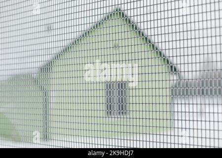 Frost auf Stahlgeflecht. Zaunnetz im Winter. Zaun um das Haus. Haus außerhalb der Stadt. Stockfoto