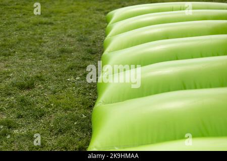 Grünes Trampolin. Aufblasbare Rutsche. Hindernisparcours. Unterhaltung im Park. Gummibauteile. Stockfoto