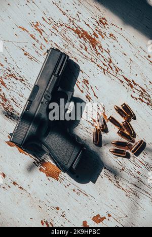 Eine halbautomatische Pistole aus Österreich, Glock aus dem Jahr 9mm, die auf einem Holztisch sitzt, zusammen mit 9mm Kugeln. Stockfoto