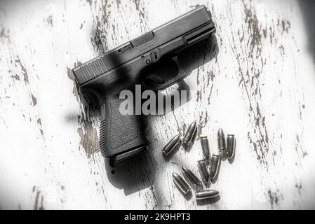 Eine halbautomatische Pistole aus Österreich, 9mm Glock 19, die auf einem Holztisch ruht, zusammen mit einer Gruppe von 9mm Kugeln. Stockfoto