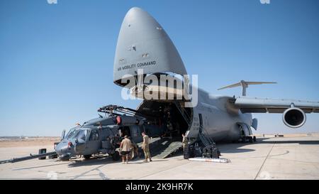 Flieger der 1. Expeditionary Rescue Group und des 60. Air Mobility Wing, Travis Air Force Base, entladen einen HH-60 Pave Hawk Hubschrauber zusammen mit anderen Ladungen aus einer C-5M Galaxy an einem nicht bekannt gegebenen Ort, Südwestasien, 11. Oktober 2022. Die C-5 verfügt über eine starke strategische Luftbrücke mit interkontinentaler Reichweite und ist als eines der größten Militärflugzeuge der Welt in der Lage, übergroße Lasten zu tragen. (USA Air Force Foto von Tech. Sgt. Jeffery Foster) Stockfoto