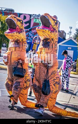 10-22-2022 Tulsa USA - Dinosaurier auf der Stadt - zwei Frauen in aufblasbaren T-Rex Kostümen mit Handtaschen und Quick Trip Styropor-Trinkbecher überqueren den Zeitraum Stockfoto