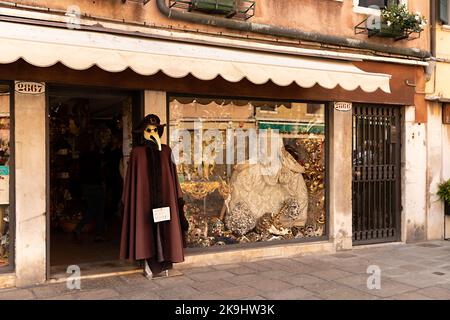 Der Laden in Venedig mit traditioneller venezianischer Kleidung für Karneval und Pestarzt-Kostüm auf der Vitrine Stockfoto