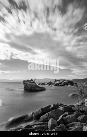 Ein Schwarzweiß-Foto zeigt eine ruhige Seeszene am Lake Tahoe, Kalifornien, mit Blick auf den legendären Bonsai Rock in der Mitte. Stockfoto