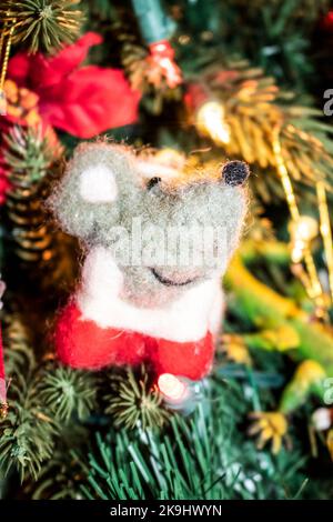 Fröhlich lächelnd gefilzte Maus hängt auf eklektischen Weihnachtsbaum - selektiver Fokus und Bokeh Stockfoto