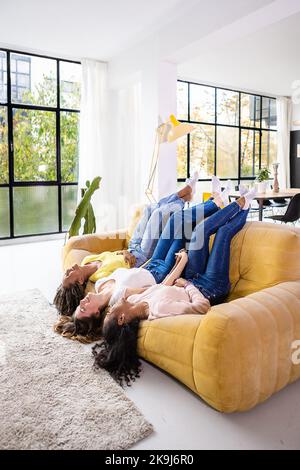 Freundschaftskonzept für Frauen mit drei verschiedenen jungen Frauen, die sich zu Hause amüsieren Stockfoto