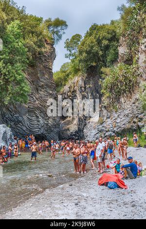 TAORMINA, ITALIEN - 9. AUGUST 2021: Im Alcantara River Park, einem beeindruckenden System aus Schluchten und Schluchten in der Nähe von Taormina, genießen die Menschen ein kaltes Wasserbad Stockfoto