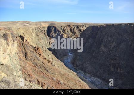 Tiefes Steinbett des Charyn Flusses in der Charyn Schlucht gegen den Himmel mit Wolken im Frühling, sonnig Stockfoto