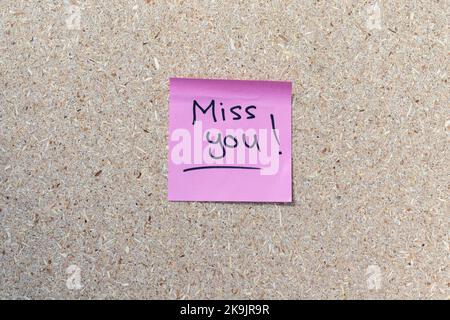 Eine handgeschriebene Erinnerungsnotiz eines Textes Miss You auf einer pinken Haftnotiz Stockfoto