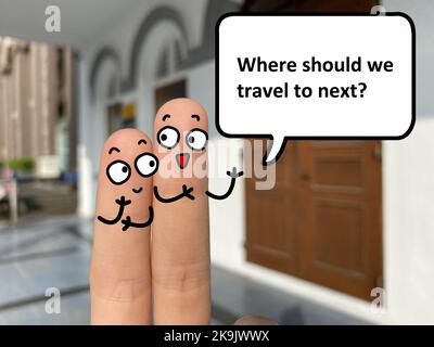 Zwei Finger sind als zwei Personen dekoriert. Einer von ihnen fragt, wohin er als nächstes reisen soll. Stockfoto