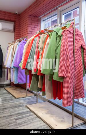 Bunte Damenkleider, Jacken, Hosen und andere Kleidung an Kleiderbügeln in einem Einzelhandelsgeschäft. Das Konzept von Mode und Shopping. Damenbekleidung im Kampf Stockfoto