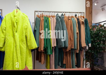 Bunte Damenkleider, Jacken, Hosen und andere Kleidung an Kleiderbügeln in einem Einzelhandelsgeschäft. Das Konzept von Mode und Shopping. Damenbekleidung im Kampf Stockfoto