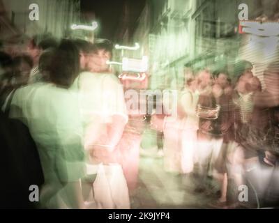 Verschwommener Effekt der städtischen Menschenmenge und des Nachtlebens in der europäischen Stadt Paris. Stockfoto