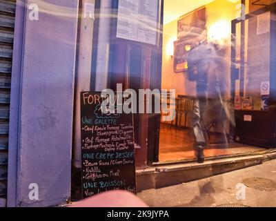 Paris Frankreich - 2009. Juni; verschwommene Person beim Betreten des Restaurants an der Tafel im Viertel Montmartre vorbei. Stockfoto