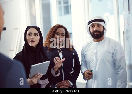 Konzentriert sich auf den Plan. Eine Gruppe verschiedener Geschäftskollegen, die in ihrem Büro an einem Whiteboard zusammenarbeiten. Stockfoto