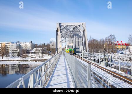 SAVONLINNA, FINNLAND - 03. MÄRZ 2018: Eisenbahnbrücke mit vorbeifahrenden Personenzug im Stadtbild am Nachmittag des März Stockfoto