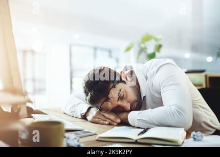 Dreamland ist der einzige Ort, an dem er sein möchte: Ein junger Geschäftsmann, der an seinem Schreibtisch in einem Büro schläft. Stockfoto