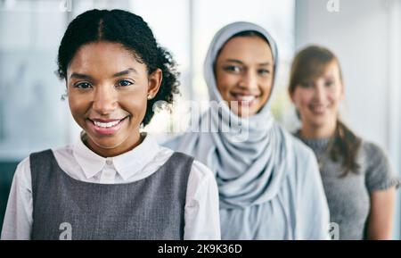 Sie sind immer motiviert, ihr Bestes zu geben. Porträt einer Gruppe junger, selbstbewusster Geschäftsfrauen, die in einer Reihe hintereinander im Inneren des stehen Stockfoto