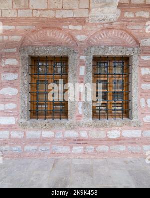 Zwei angrenzende hölzerne Bogenfenster in einer alten rot-weißen Ziegelsteinmauer, in der Nähe von Eyup Sultan Mosqoe, Istanbul, Türkei Stockfoto