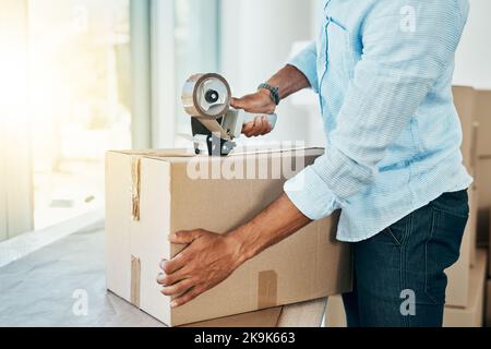 Alles verpackt und bereit zum Umzug. Schoss einen jungen Mann, der eine Schachtel versiegelte, während er das Haus umzog. Stockfoto