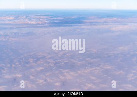 Hintergrund eines rosa himmlischen Himmels mit flauschigen dichten Wolken, Draufsicht aus einem Flugzeug. Kann als Werbehintergrund, Overlay verwendet werden. Reisekonzept. Stockfoto