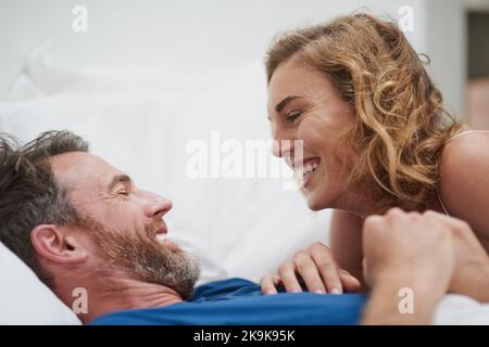 Hallo mein schöner Mann. Ein glückliches Paar mittleren Alters, das sich im Bett zusammen entspannt. Stockfoto