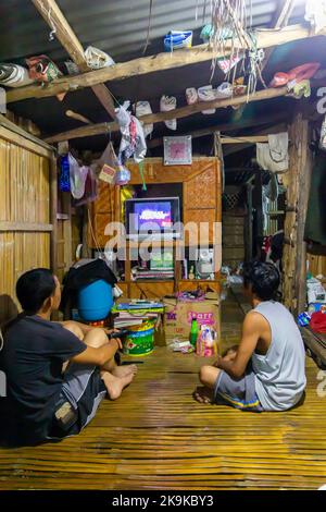 Zwei philippinische Männer schauen fern in ihrem Heimathaus in Batangas, Philippinen Stockfoto