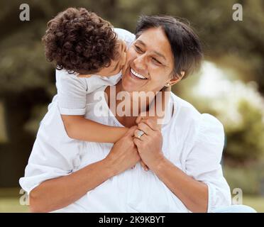 Umarmung, Kuss und Großmutter mit einem Kind in einem Park mit Liebe, Freiheit und Fürsorge für die Familie. Glücklich, lächeln und ältere Frau umarmt ein Kind mit Zuneigung Stockfoto