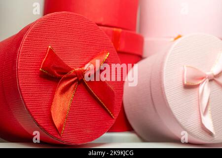 Zwei zylindrische Geschenkboxen, rot und rosa, mit Satinbändern Seitenansicht aus nächster Nähe Stockfoto