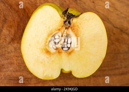 Die Hälfte der Quitten-Früchte, Nahaufnahme auf einem defokussten Holzbrett-Hintergrund Stockfoto